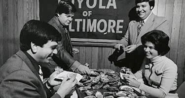 An old black and white photo of students eating oysters and crabs around a table